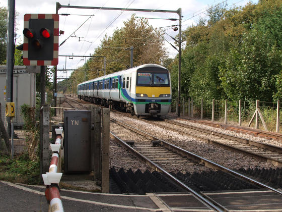 An electric commuter train approaching a level crossing